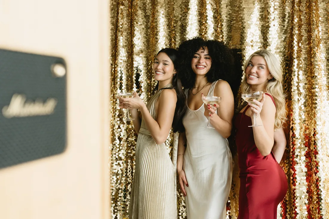Guests toasting at an open-air photo booth with a gold sequin backdrop